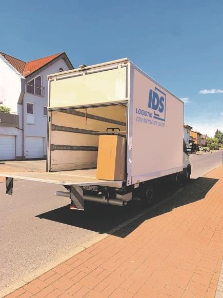 Open van with a load of cardboard boxes on a residential street.