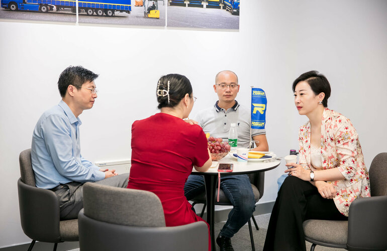 4 Menschen sitzen um einen Tisch und unterhalten sich.
