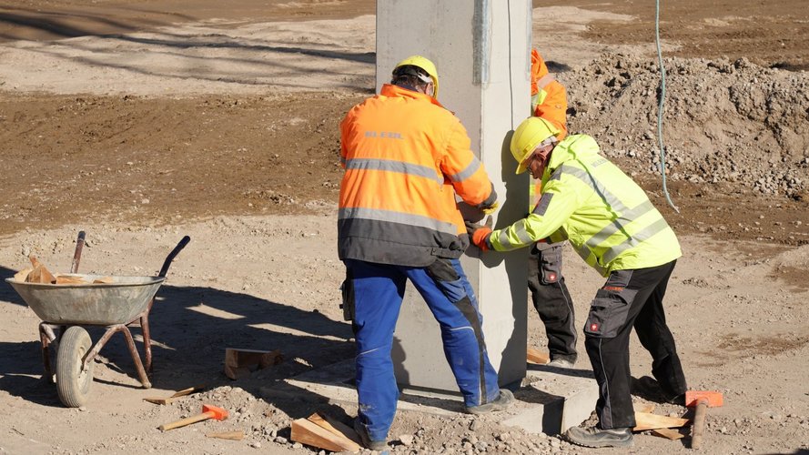 3 construction workers helping to place the pillar