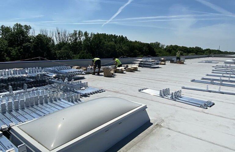 Einige Arbeiter, die das Dach mit Solarpanelen austatten.