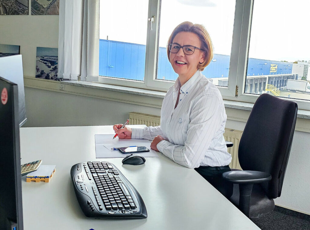 eine lachende Frau vor einem PC.
