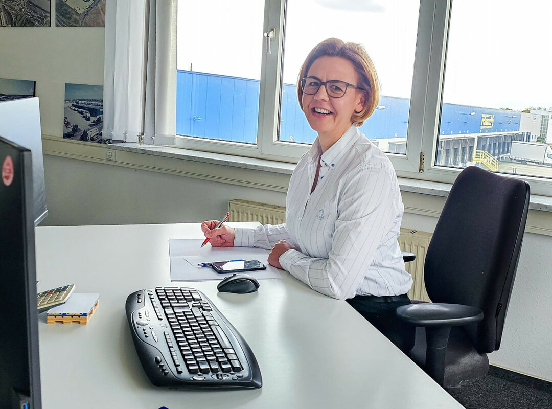 eine lachende Frau vor einem PC.