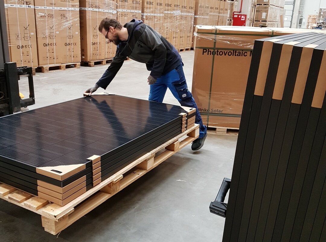 Ein Mann sichtet eine Palette voller Solarpanele.