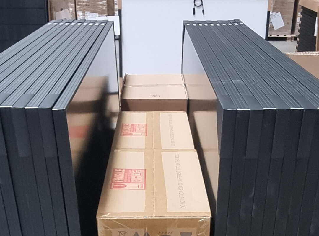 Gestapelte schwarze Rahmen und Kartons in einem Lagerraum.