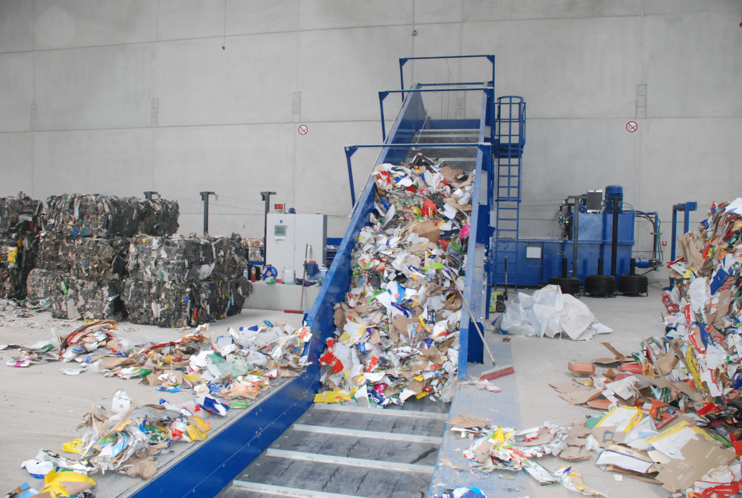 Maschine sortiert und transportiert Papiermüll in einer Recyclinganlage.