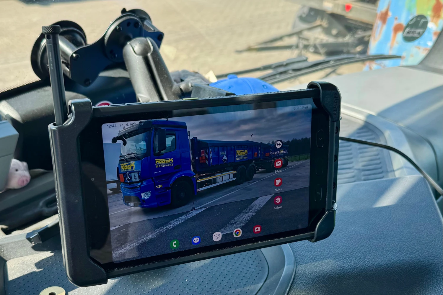 Tablet mit Kameraaufnahme eines blauen LKWs, befestigt an der Windschutzscheibe eines Fahrzeugs.