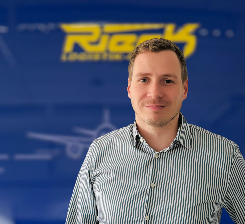 Mann mit gestreiftem Hemd vor blauem Hintergrund mit gelbem Schriftzug.